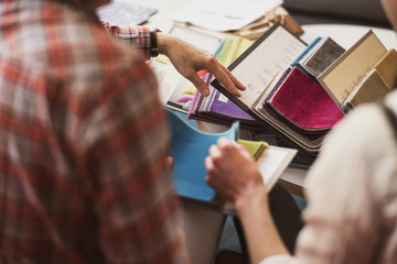 Cropped image of owner with customer choosing fabric swatch at store