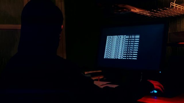 Hacker in the room in front of a computer monitor.