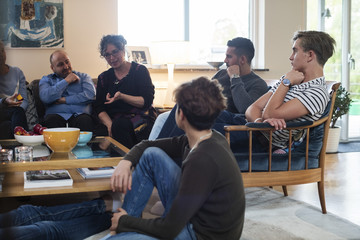 Multi-ethnic friends and family talking while sitting in living room