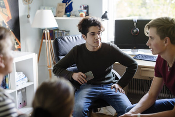 Siblings talking to friend while sitting in bedroom