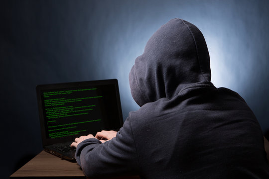 Hacker with laptop initiating cyber attack