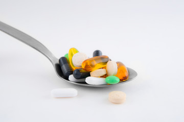 Multivitamins and pills on the spoon on white background	