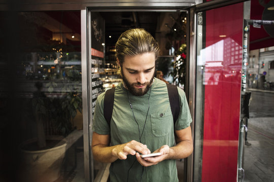 Man using smart phone against restaurant in city