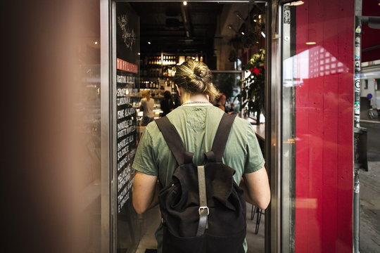 Rear view of man with backpack entering restaurant