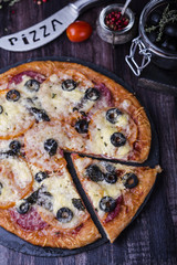 pizza with salami, mozzarella, olives and basil