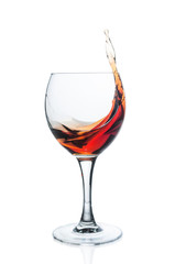 Splashing red wine in glass on white background