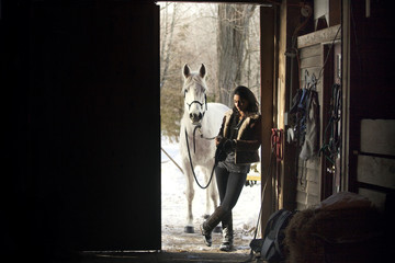 Woman with white horse in shed