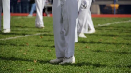 View of the legs of marching band members preforming a halftime show during the day-2.