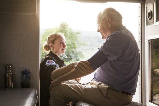 Paramedic Examining Senior Patient In Ambulance