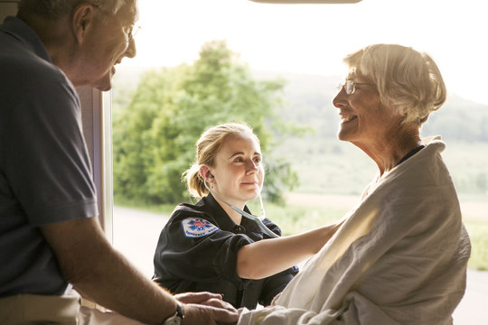 Paramedic taking care of senior patient sitting in ambulance
