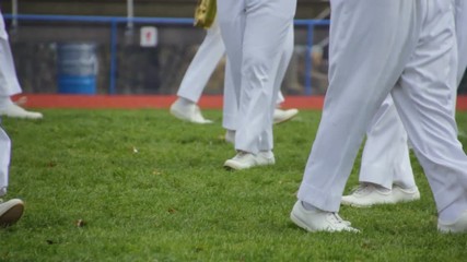 View of the legs of marching band members preforming a halftime show during the day-1.