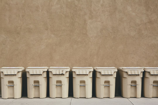 Row of recycling containers along sidewalk and street