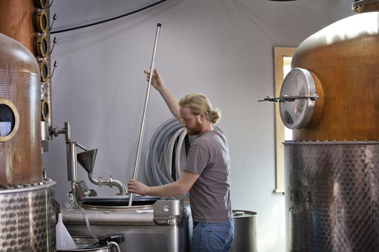 Distillery worker stirring vat