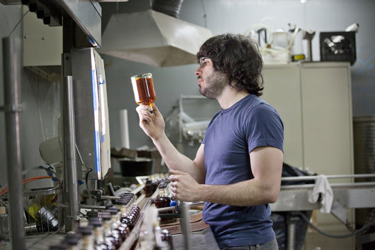 Distillery worker quality checking whiskey