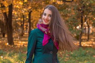 girl with straight long hair stands in autumn Park and smiles