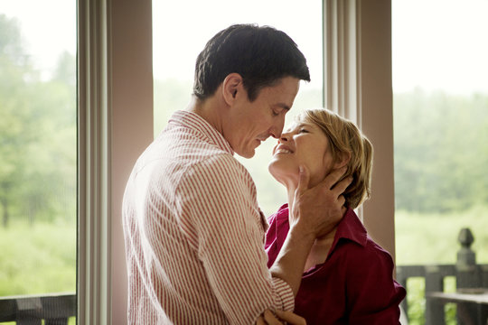 Couple kissing by window at home