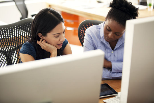 Women sitting at desk and working at tablet