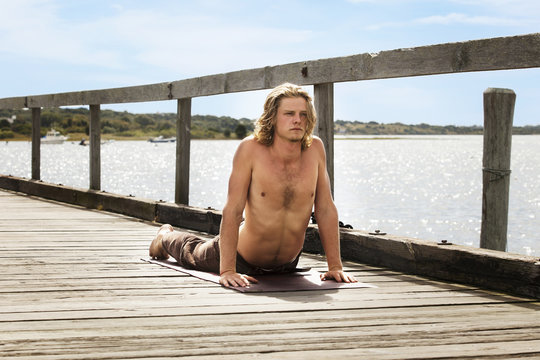 Young man stretching on pier