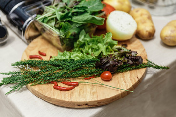Fresh Ingredients Include Rosemary, Onion, Tomato, Potato and Vegetables on Wood Block. 