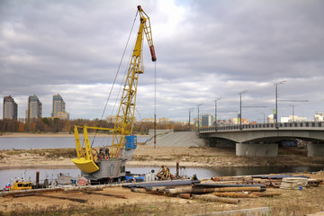 Fototapeta na wymiar Crane and pipes on a ground during bridge repairing