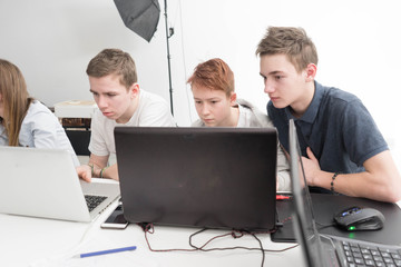 a young boy with a laptop working. students in the class. Teenagers working at his laptop. Lesson at school. Two friends at school. serious student