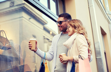 happy couple with shopping bags and coffee in city