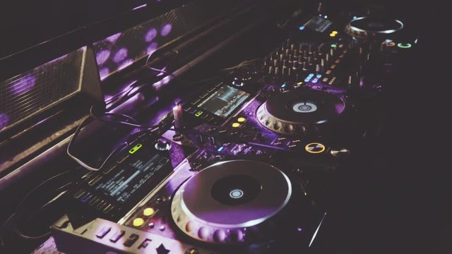 behind dj decks and mixer in night club, staic angle shot