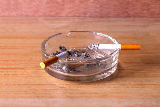 cigarettes in ash-tray on wooden background
