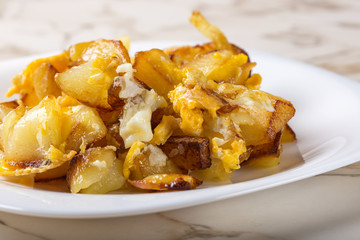 Fries with smashed eggs on white plate