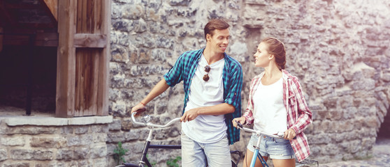 Young couple of hipsters riding a bicycle. Date in old town. Love, relationship, romance concept.
