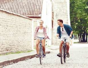 Young couple of hipsters riding a bicycle. Date in old town. Love, relationship, romance concept.