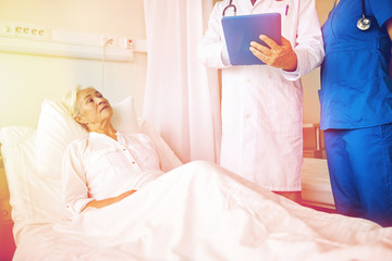 doctor and nurse visiting senior woman at hospital