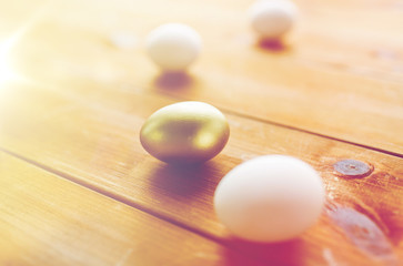close up of golden and white easter eggs on wood