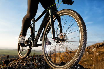 closeup feet athlete mountainbiker and wheels of a sports bicycle