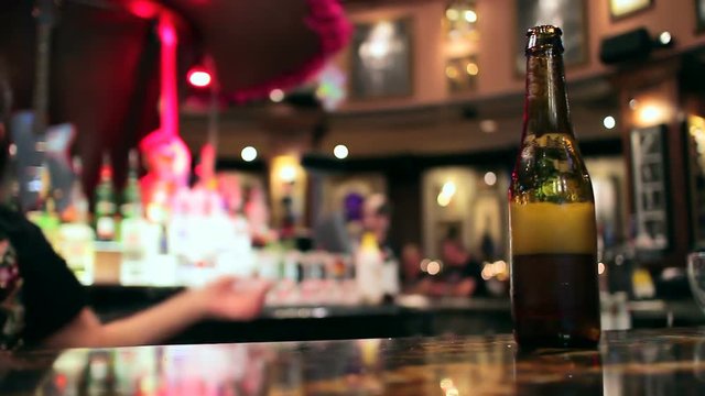 Bottle of beer sitting on a bar.