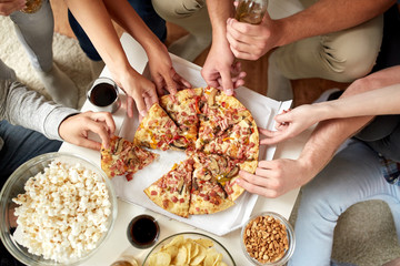 close up of people taking pizza slices at home