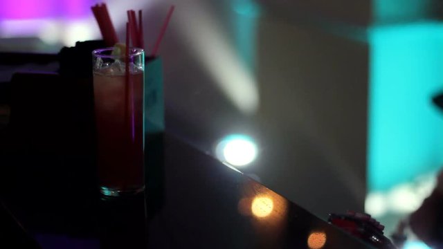 Man grabbing two mixed drinks from a bartender in a club.