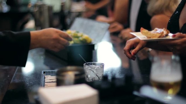 Bartender pours a mixed drink at a wedding bar.