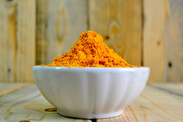Tumeric powder in a bowl isolate on wooden background