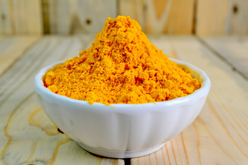 Tumeric powder in a bowl isolate on wooden background