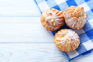 Homemade profiteroles with cream on white wooden table