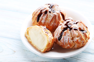 Homemade profiteroles with cream on white wooden table