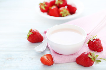 Strawberry yogurt in bowl on wooden table