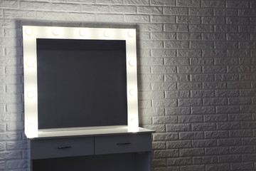 Makeup mirror with lightbulbs on brick wall background