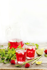 Fresh strawberry drink in glass with lime on wooden table