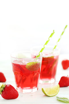 Fresh strawberry drink in glass with lime on wooden table