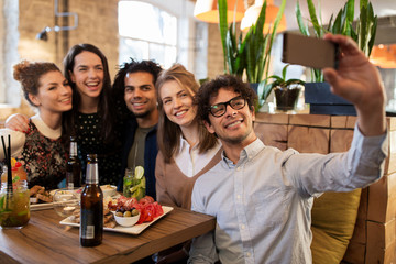 friends taking selfie by smartphone at bar or cafe