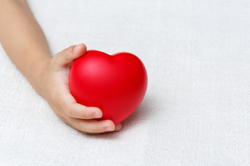 Red heart in baby palm hands