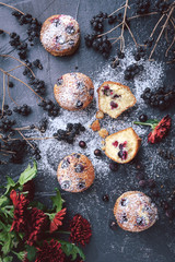 muffin with currants on a dark background next to the berries on the branches. and a bouquet of flowers. in a rustic style. dark style