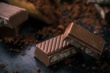 Detail of chocolate with creamy filling on black board with cocoa